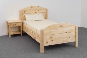 Einzelbett Breitenstein, Massivholzbett aus Zirbenholz, Kopfhaupt und Fußhaupt mit Segmentbogen, Eckpfosten gerundet, Abb. mit optionalen Nachtkästchen und optionalem ergonomischen ProNatura-Schlafsystem - Original Steiner Zirbenbett