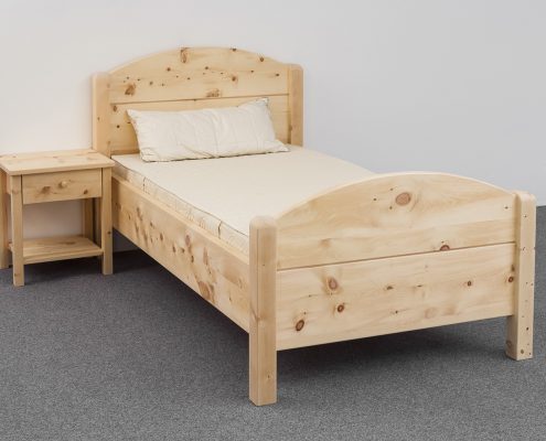 Einzelbett Breitenstein, Massivholzbett aus Zirbenholz, Kopfhaupt und Fußhaupt mit Segmentbogen, Eckpfosten gerundet, Abb. mit optionalen Nachtkästchen und optionalem ergonomischen ProNatura-Schlafsystem - Original Steiner Zirbenbett