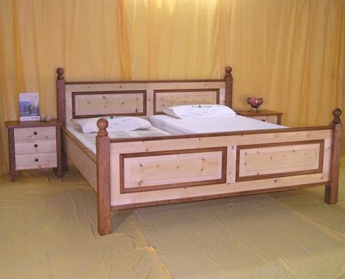 Doppelbett Heuberg mit Nachtkästchen, detailreich kombiniert mit Apfelbaumholz; Kopfhaupt und Fußwange mit abgeplatteten, gerahmten Füllungen, Aufsatzleisten und gedrechselte Eckpfosten aus Apfelbaum mit Kugelaufsatz - Original Steiner Zirbenbett