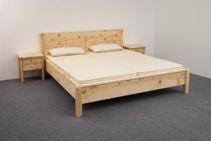 Doppelbett Rotwand, leicht schräge Rückenlehne und hochgezogene, geschwungene Bettpfosten am Kopfhaupt, Korpus-Kanten auf Kopfhaupt, Fußwange und Seitenwangen mit Aufsatzleisten, Bettpfosten an der Fußwange oben abgerundet, Abb. optionale mit Nachtkästchen und ProNatura-Schlafsystem - Original Steiner Zirbenbett