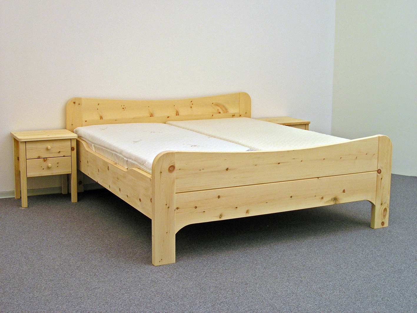 Doppelbett Wiesberg, Kopfhaupt und Fußwange mit nach innen geschwungenem Bogen, abgerundete Bettpfosten, Seitenwangen abgesenkt, Abb. mit optionalen Nachtkästchen und ergonomischem ProNatura-Schlafsystem - Original Steiner Zirbenbett