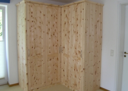 Zirbenholz-Kleiderschrank 09.3, Eckschrank aus massivem Zirbenholz, abgerundete Korpuskanten und abgerundetes Gesims, 4 Türen, abgeplattete Füllungen, Aluminium-Bügelgriffe, Ecktüren öffnen im weiten 155 Grad-Winkel, passend zu Original Steiner Zirbenbetten