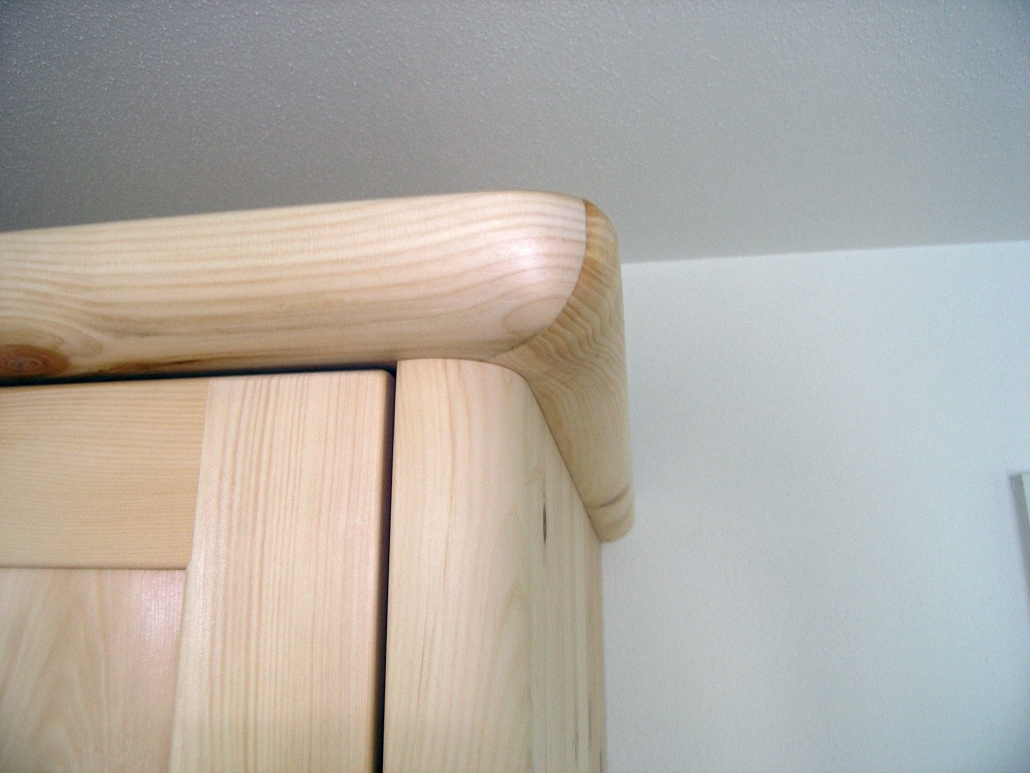Zirbenholz-Schrank 09.3, Eckschrank aus massivem Zirbenholz, Blick auf die abgerundeten Korpuskanten und das auf Gärung geschnittene, abgerundete Gesims