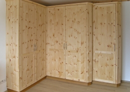 Zirbenholz-Kleiderschrank 09.6, Eckschrank aus massiver Zirbe, abgeschrägte Korpuskanten, gerades Aufsatzgesims, Eichen-Sockel, 5 Rahmentüren mit abgeplatteten Füllungen, 1 Türelement zurückgesetzt, passend zu Original Steiner Zirbenbetten