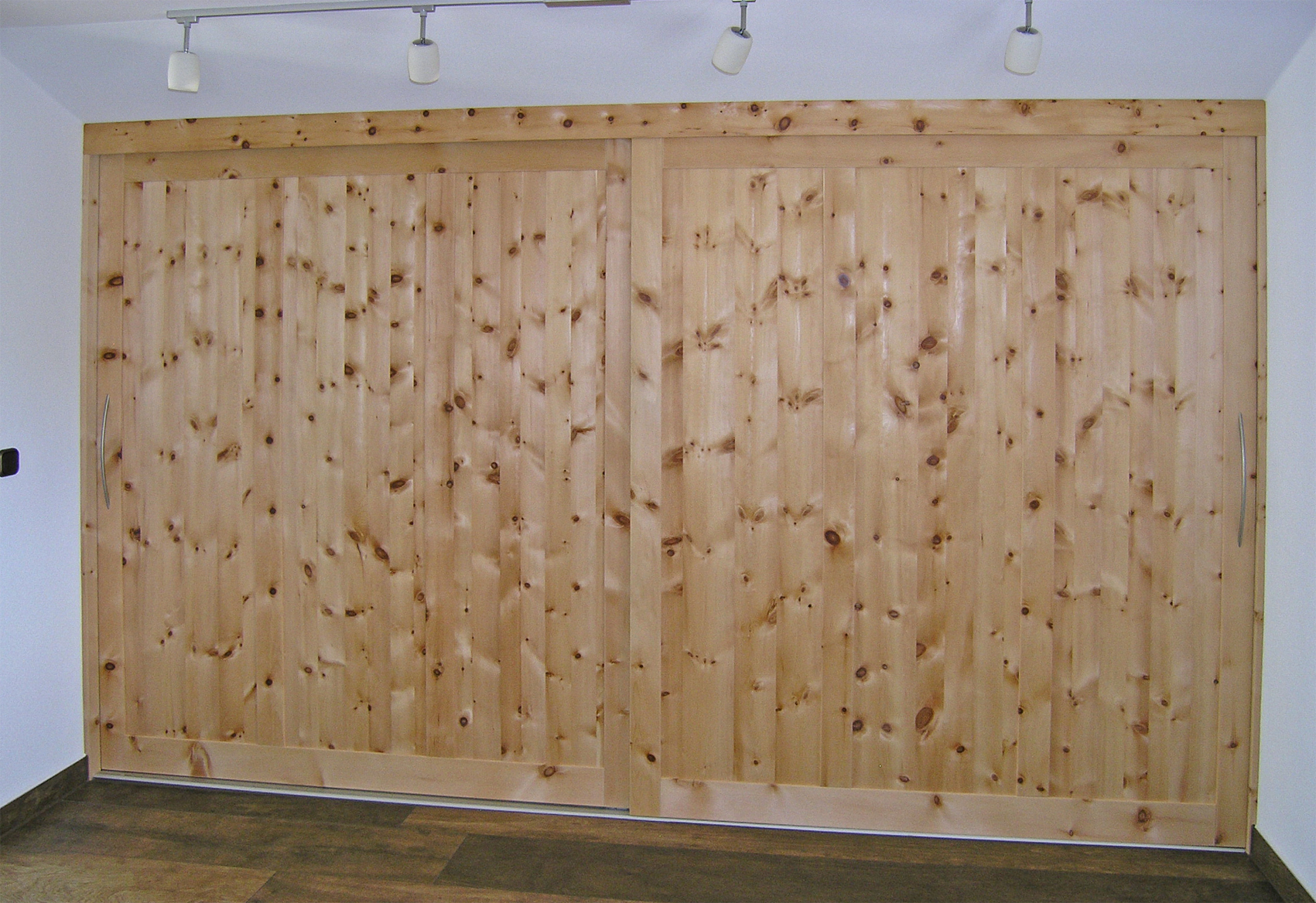 Zirbenholz-Kleiderschrank 11.0 aus massivem Zirbenholz, 2 breite Schiebetüren in Rahmenbauweise mit abgeflachten Türfronten und gebogenen Aluminiumgriffen